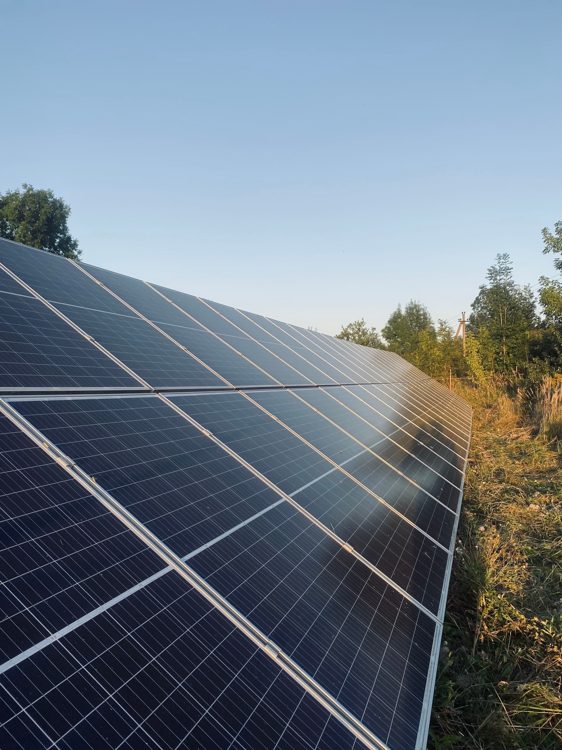A ground-mounted solar array under clear skies, generating at full capacity.